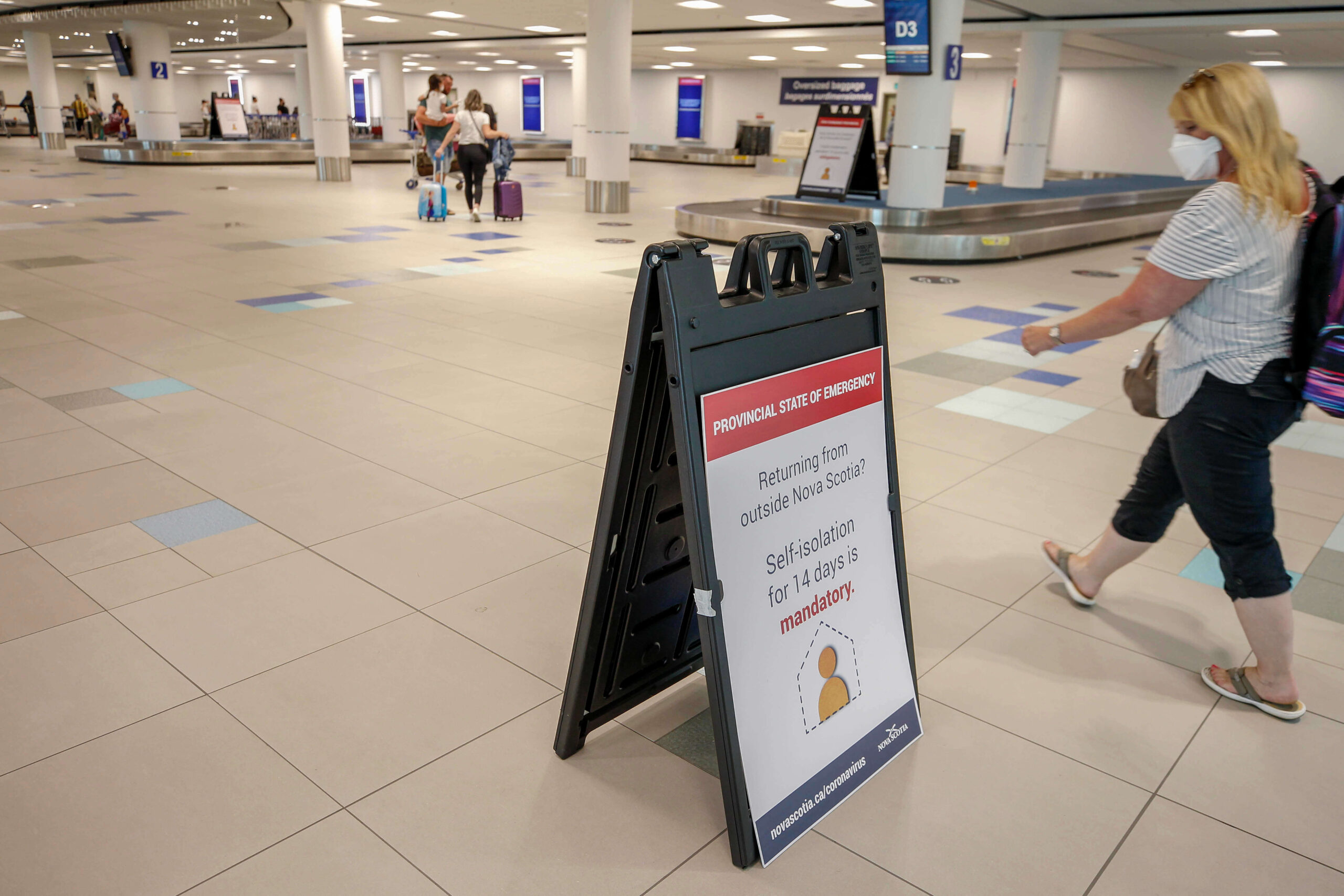 Woman reading sign about mandatory self-isolation when arriving at the airport.